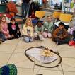 ungefähr 20 Kinder knien im Kreis und versuchen in der Mitte ein Bild zu malen